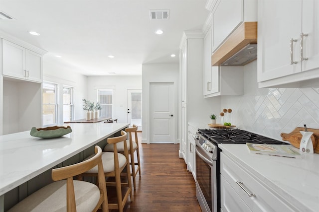 1026 Fugate St, Houston, TX 77009 - kitchen with stainless steel gas range, premium range hood, white cabinets, dark wood-style flooring, and tasteful backsplash