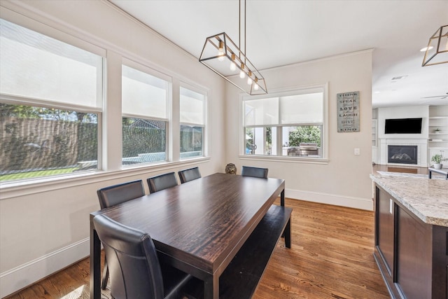 dining area with a glass covered fireplace, baseboards, and wood finished floors