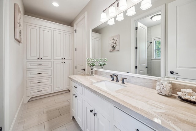 full bathroom with vanity, baseboards, and walk in shower