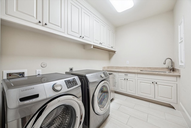 laundry area featuring washer and dryer, baseboards, a sink, cabinet space, and light tile patterned floors