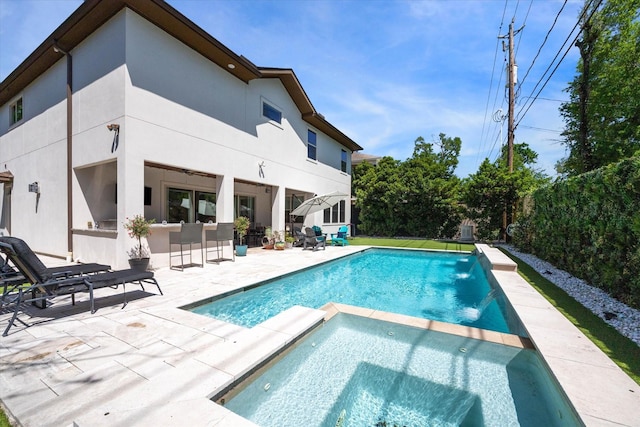 view of swimming pool with outdoor dry bar, a pool with connected hot tub, and a patio area