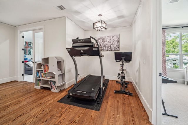 exercise area with crown molding, baseboards, wood finished floors, and visible vents