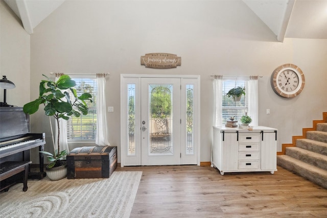 foyer featuring light wood-style flooring, stairs, and high vaulted ceiling