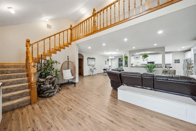 living area with arched walkways, light wood-style flooring, stairs, recessed lighting, and visible vents