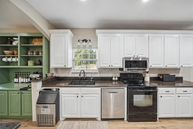 kitchen featuring white cabinets, appliances with stainless steel finishes, a sink, and dark stone countertops