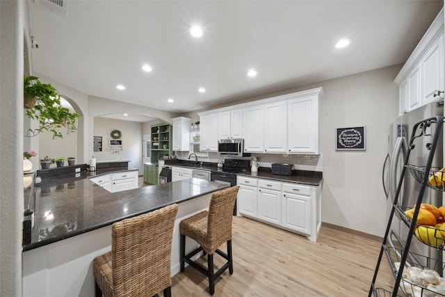 kitchen featuring white cabinets, arched walkways, appliances with stainless steel finishes, and a sink