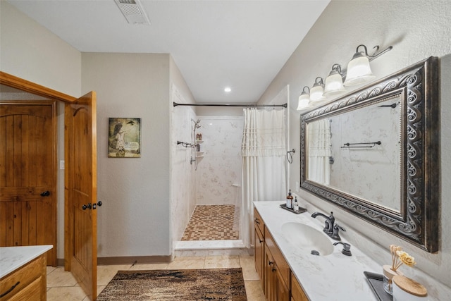 full bath featuring vanity, tile patterned floors, visible vents, and tiled shower