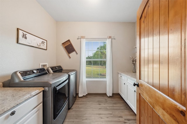 laundry area featuring baseboards, washing machine and dryer, light wood-type flooring, and cabinet space