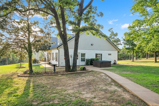 view of side of property with a lawn and a hot tub