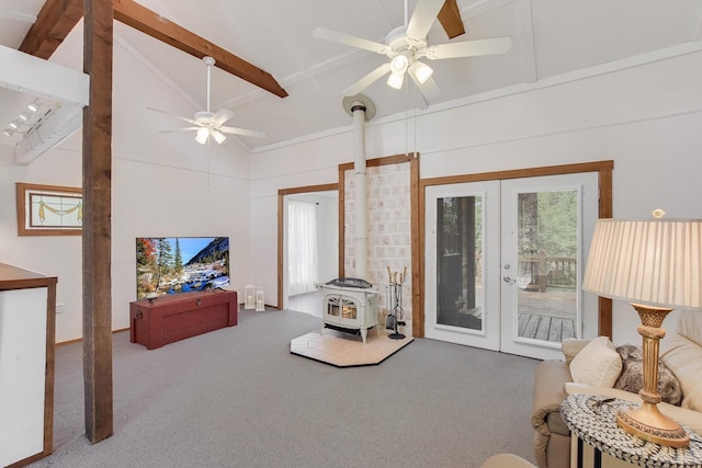living room featuring ceiling fan, french doors, a wood stove, beamed ceiling, and carpet flooring