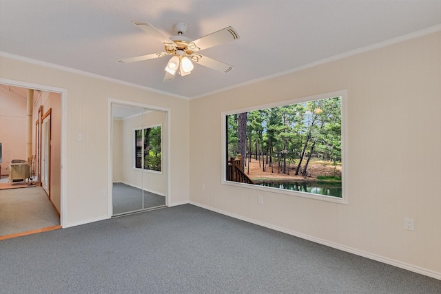 unfurnished bedroom featuring a ceiling fan, carpet floors, baseboards, a closet, and ornamental molding