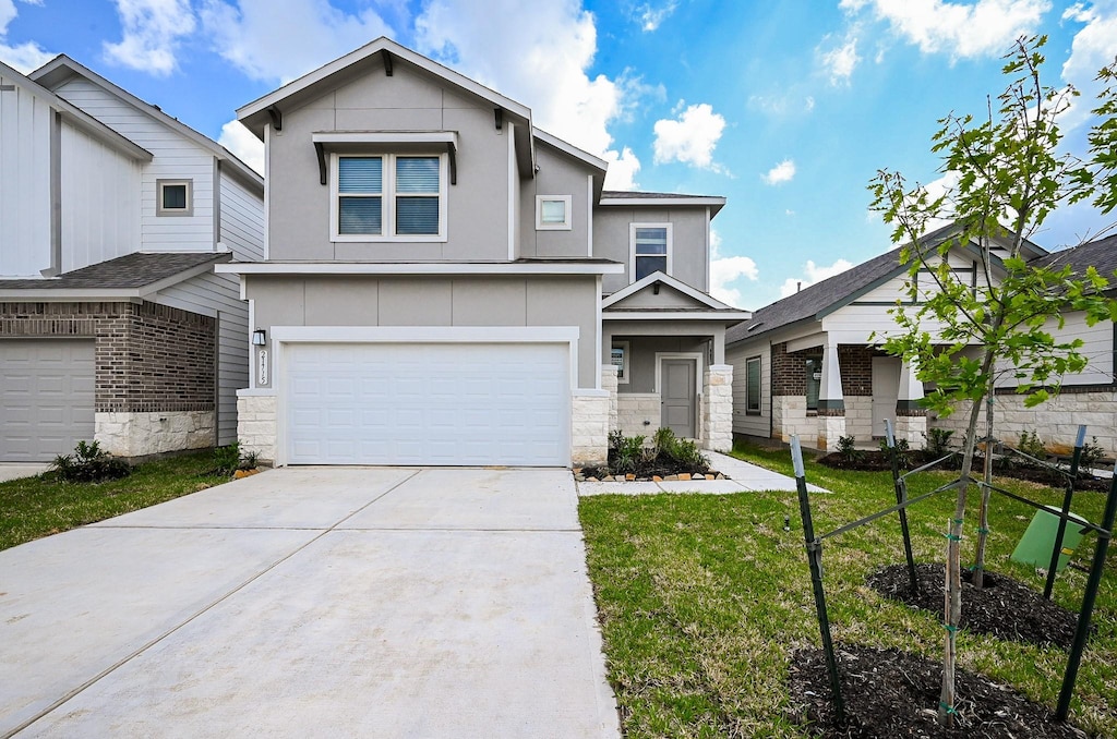 view of front of home featuring an attached garage, a front lawn, driveway, and stone siding