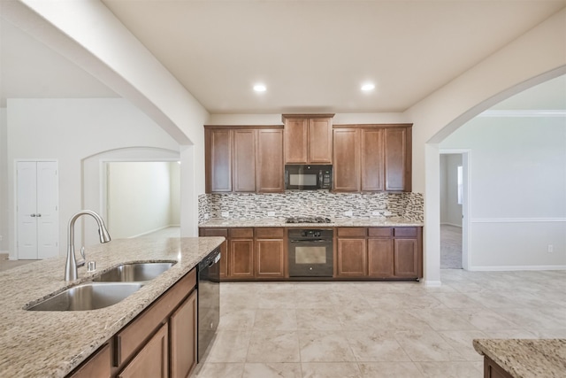 9135 Monarch Field Ln, Cypress, TX 77433 - kitchen featuring a sink, arched walkways, black appliances, and light stone countertops