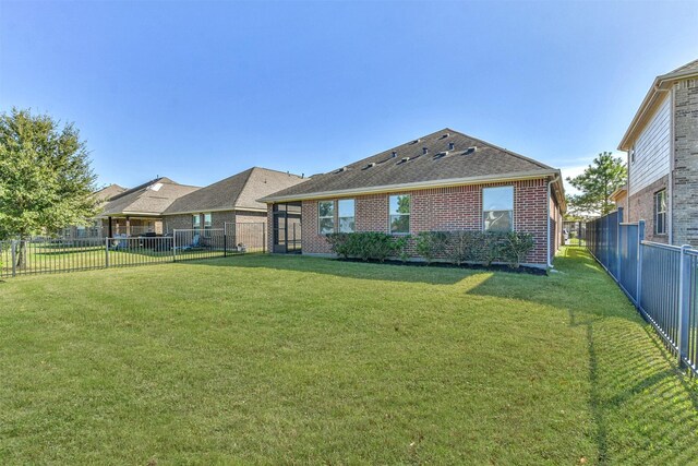 9135 Monarch Field Ln, Cypress, TX 77433 - rear view of house with a fenced backyard, a shingled roof, a yard, and brick siding