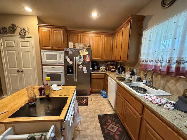 8813 Lauren Ln, Waller, TX 77484 - kitchen with a sink, white appliances, decorative backsplash, light tile patterned floors, and butcher block counters