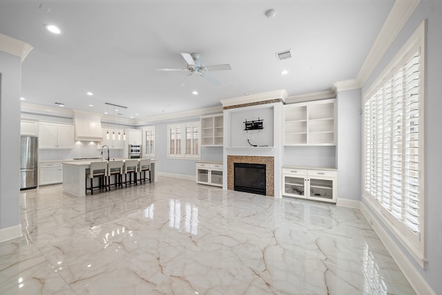 living area featuring crown molding, visible vents, marble finish floor, baseboards, and ceiling fan