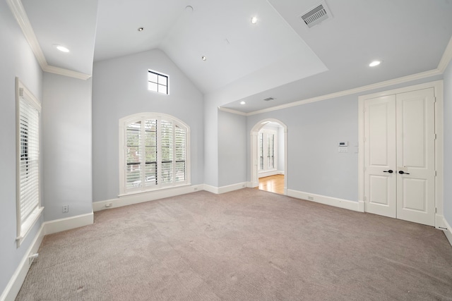 unfurnished living room featuring arched walkways, visible vents, ornamental molding, and carpet