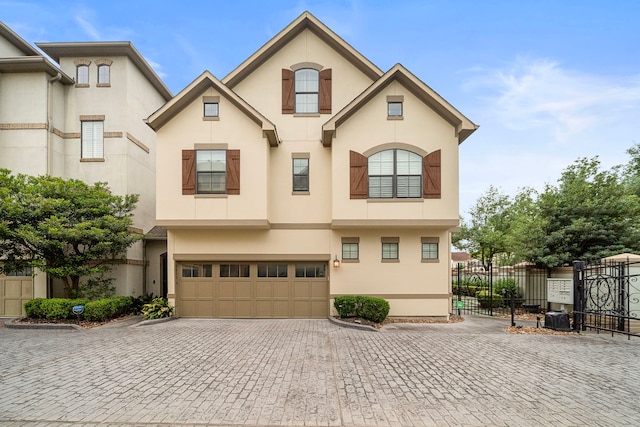 multi unit property with a gate, a garage, decorative driveway, fence, and stucco siding