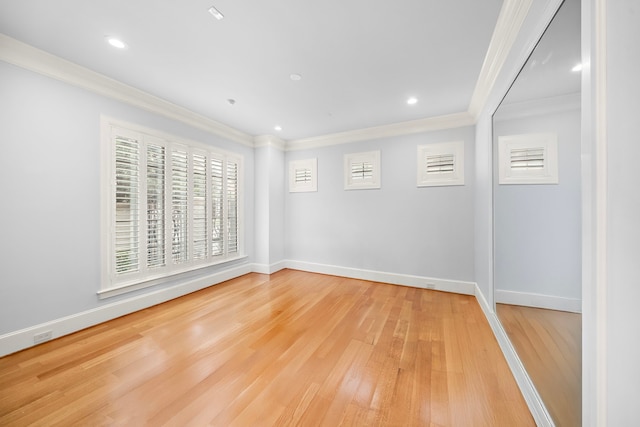 spare room with baseboards, ornamental molding, and light wood-style flooring