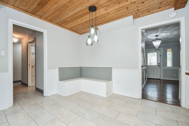 709 N Rivershire Dr, Conroe, TX 77304 - unfurnished dining area featuring ornamental molding, a wainscoted wall, wooden ceiling, light tile patterned floors, and a notable chandelier