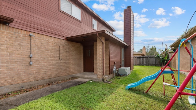 exterior space with brick siding, a lawn, fence, and a chimney