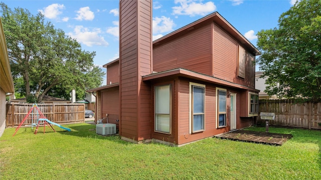 back of house with a lawn, central air condition unit, a chimney, and a fenced backyard