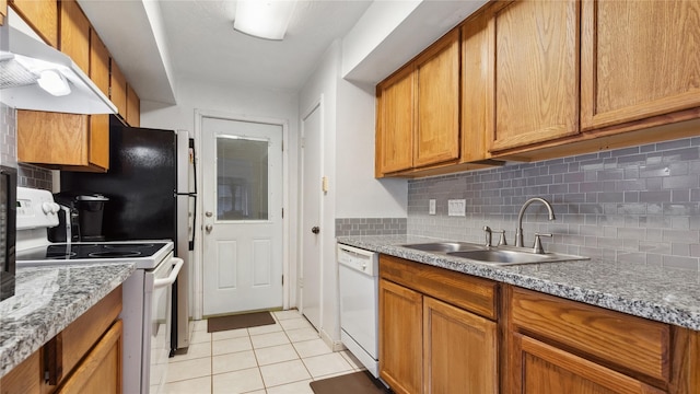 kitchen with a sink, white appliances, decorative backsplash, light tile patterned floors, and under cabinet range hood