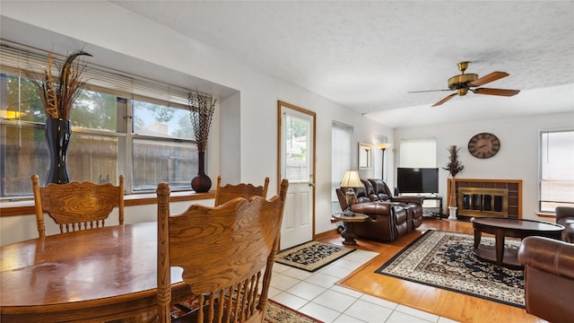 dining space featuring tile patterned flooring, ceiling fan, and a fireplace