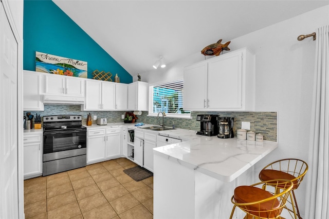 kitchen featuring stainless steel range with electric cooktop, a sink, a peninsula, lofted ceiling, and under cabinet range hood