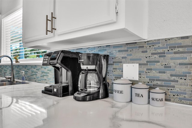 interior details with light stone counters, a sink, decorative backsplash, and white cabinets