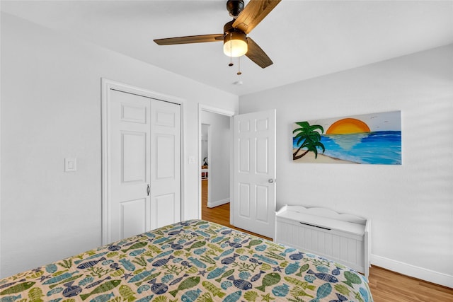 bedroom featuring baseboards, ceiling fan, wood finished floors, and a closet