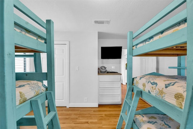 bedroom with baseboards, light wood-style flooring, and visible vents