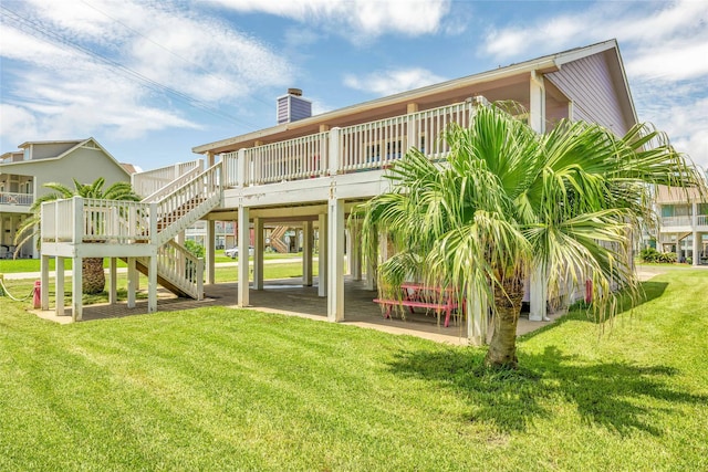 rear view of property with stairs, a chimney, a yard, and a deck