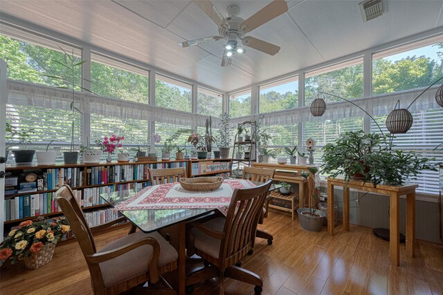 sunroom / solarium with visible vents, a wooden deck, wood finished floors, and a healthy amount of sunlight