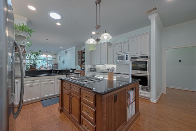 kitchen featuring a kitchen island, visible vents, appliances with stainless steel finishes, light wood-type flooring, and ornamental molding