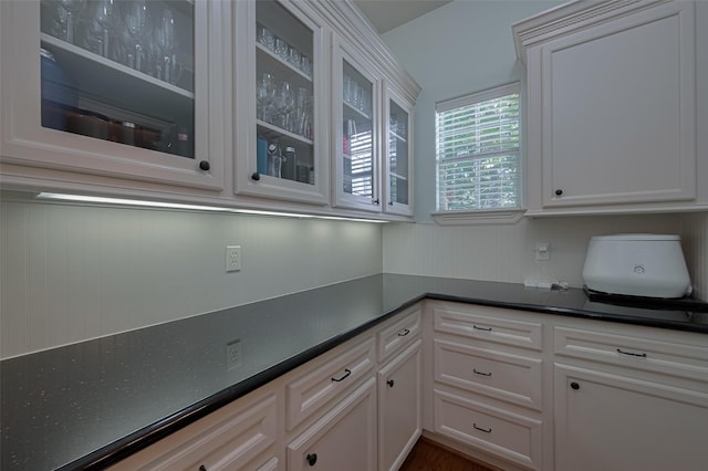 kitchen featuring glass insert cabinets, dark countertops, and white cabinets