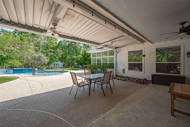 view of patio / terrace featuring a ceiling fan, an outdoor pool, an outdoor structure, a storage unit, and outdoor dining space