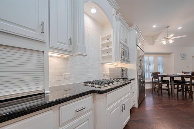 kitchen with dark wood-style flooring, built in appliances, a ceiling fan, white cabinetry, and backsplash