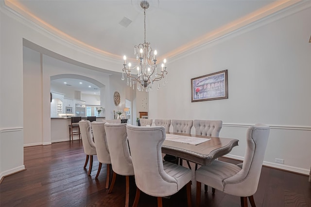 dining room featuring arched walkways, ornamental molding, dark wood-style flooring, and a notable chandelier