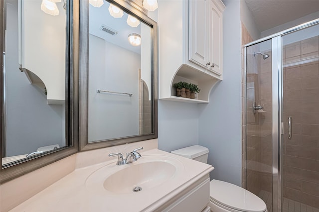bathroom featuring visible vents, a stall shower, toilet, and vanity