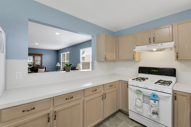 kitchen featuring white gas stove, light countertops, light brown cabinets, under cabinet range hood, and recessed lighting