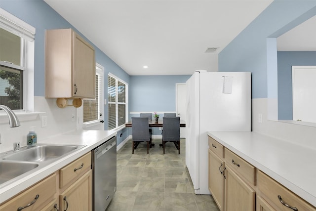 kitchen with stainless steel dishwasher, light countertops, a sink, and light brown cabinets