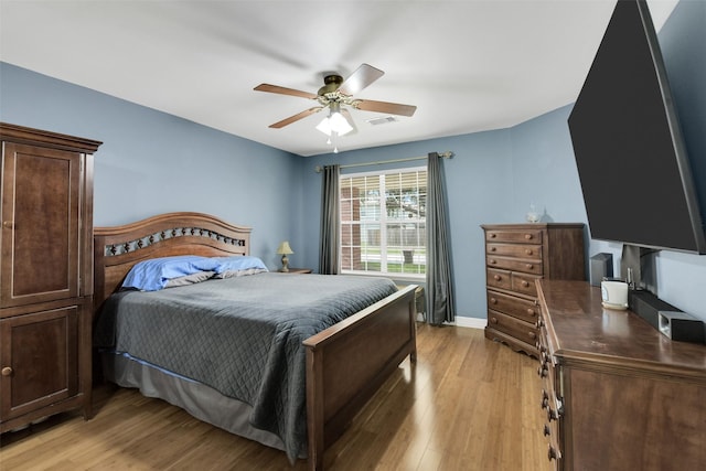 bedroom featuring light wood-type flooring, a ceiling fan, baseboards, and visible vents