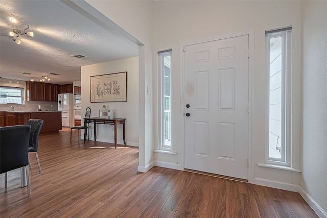 14811 El Miranda Dr, Houston, TX 77095 - entrance foyer with dark wood-style flooring, a textured ceiling, visible vents, track lighting, and baseboards