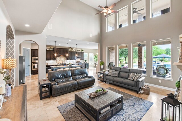 24818 Waterstone Estates Cir W, Tomball, TX 77375 - living area with ceiling fan, arched walkways, baseboards, light tile patterned floors, and a towering ceiling