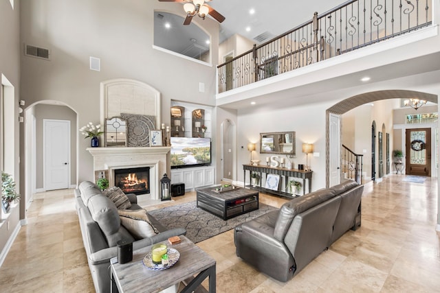 24818 Waterstone Estates Cir W, Tomball, TX 77375 - living area with visible vents, arched walkways, ceiling fan with notable chandelier, a high ceiling, and stairs