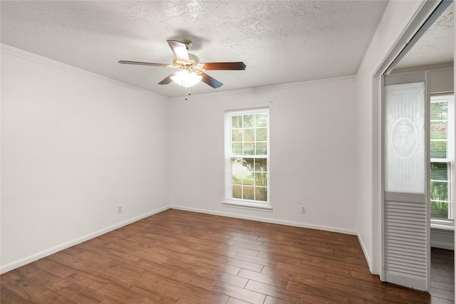 empty room with baseboards, a textured ceiling, ceiling fan, and wood finished floors