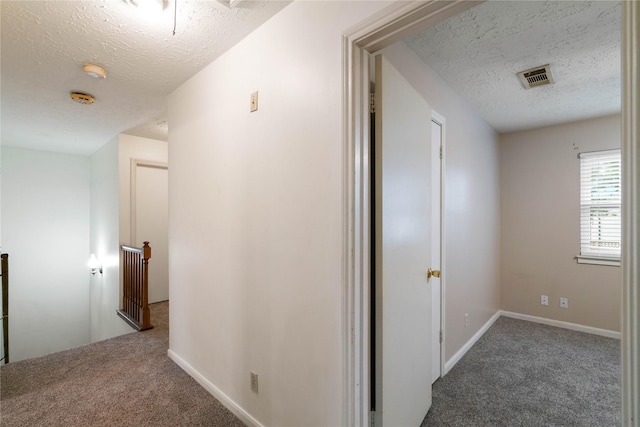 corridor featuring carpet flooring, a textured ceiling, and an upstairs landing