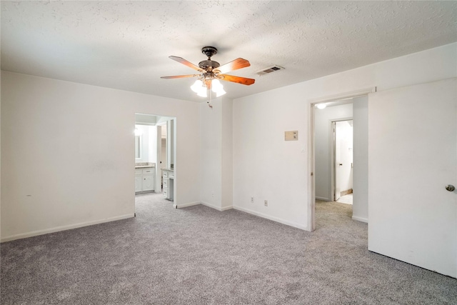 carpeted spare room featuring baseboards, ceiling fan, a textured ceiling, and visible vents