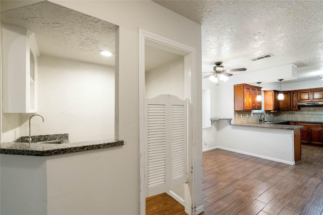 kitchen with ceiling fan, a textured ceiling, dark wood-type flooring, backsplash, and visible vents